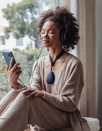 woman wearing a sensate device on her chest watching her phone with a calm relaxed face