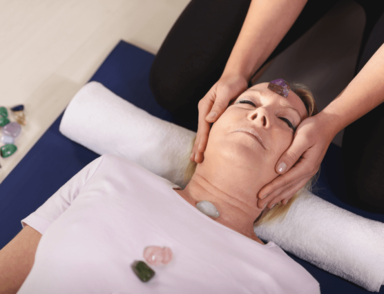 Young therapist Arranging Crystals on Female Client for Reiki Therapy